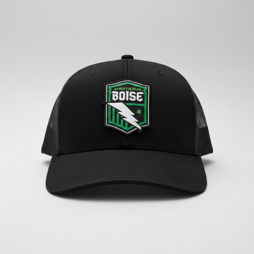 Black cap with a green and white logo on a dark surface