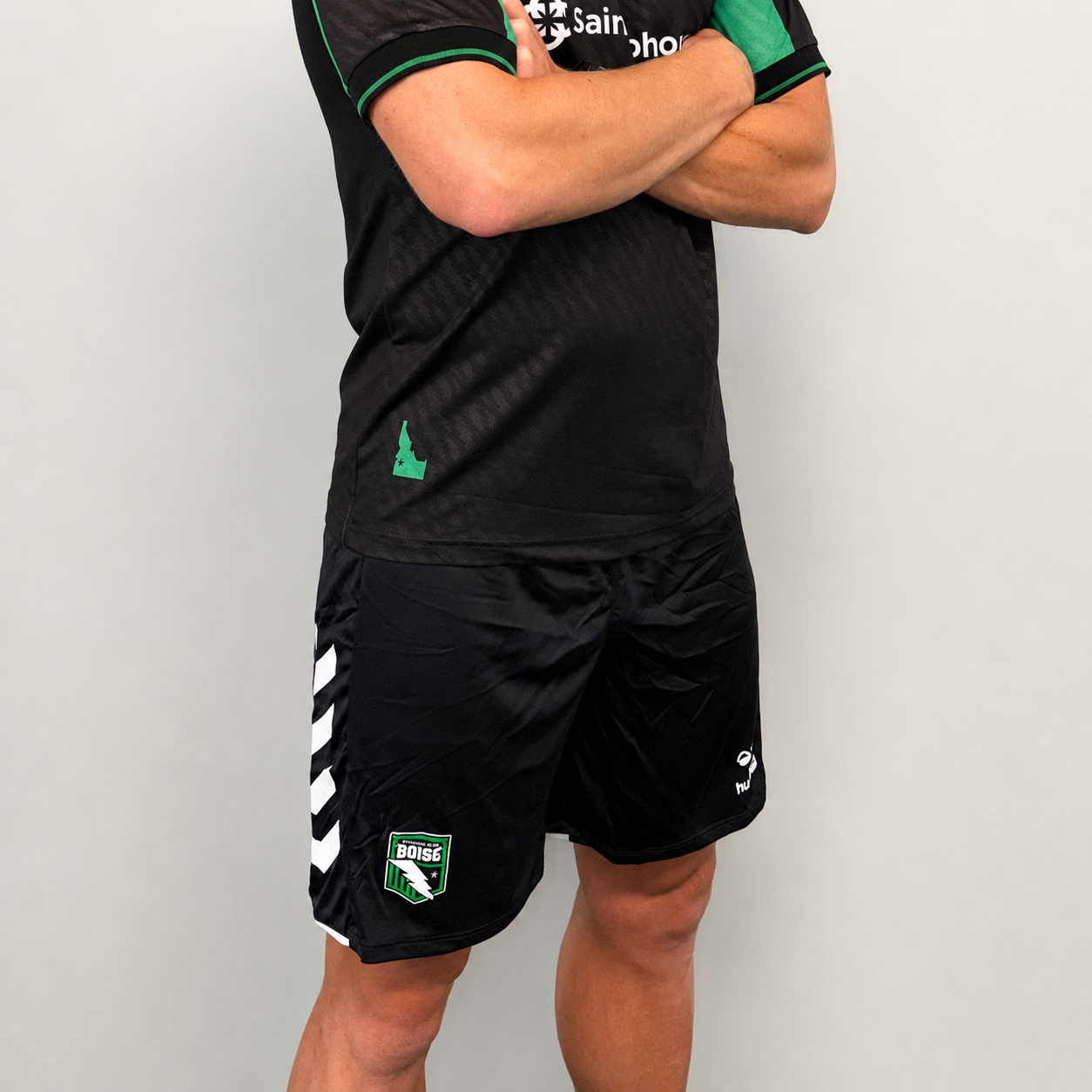 Person wearing a black sports outfit with green and white accents on a gray background